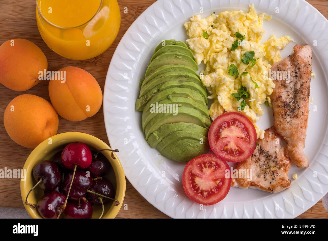 Obst und ein Teller mit Rührei, Avocado und Hühnerfilet Stockfoto