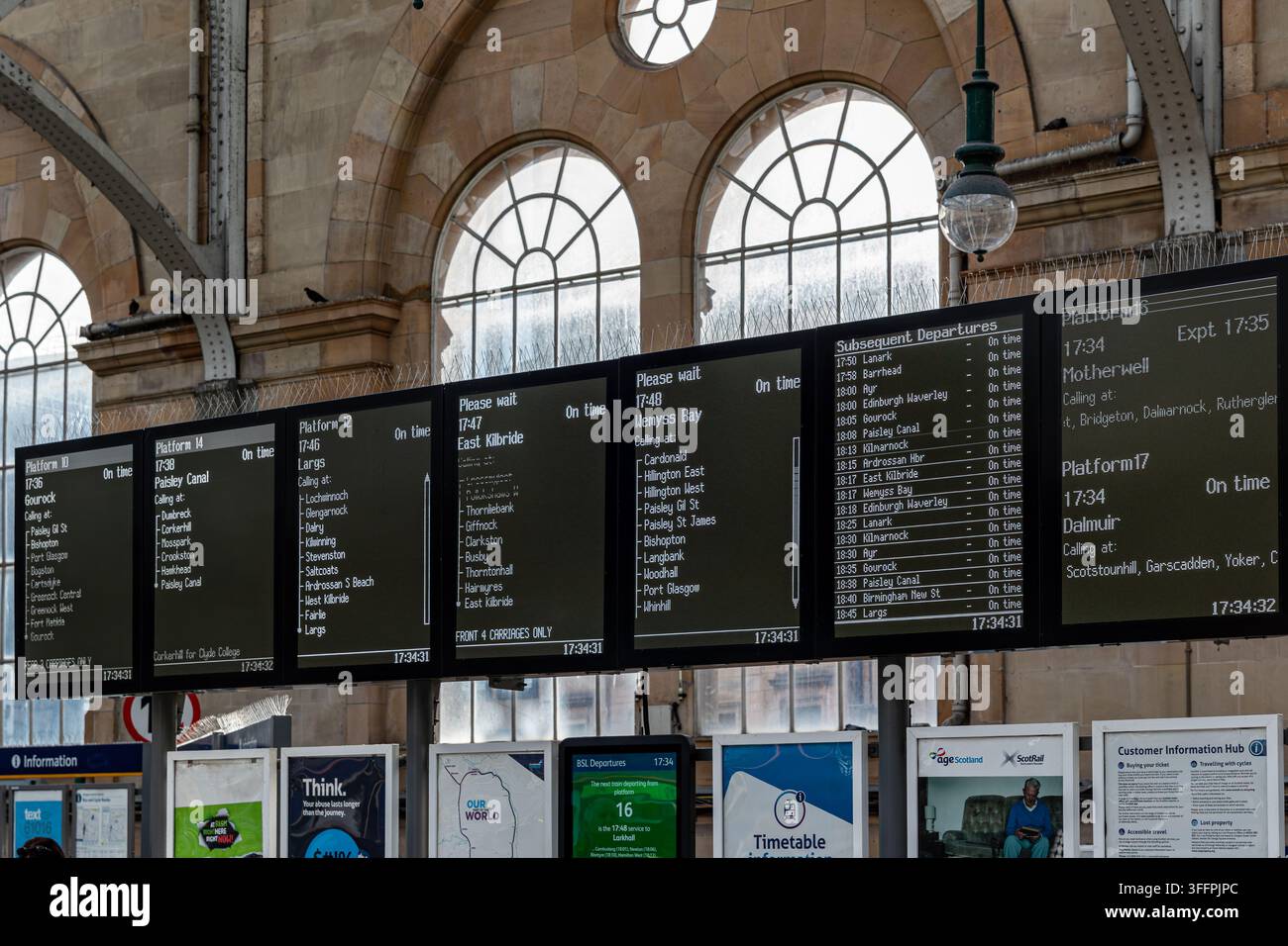 Digitale Abfahrtstafeln zeigen Zugfahrpläne an einem historischen Bahnhof mit gewölbten Fenstern und Metallrahmen in Glasgow, Schottland, UK. Stockfoto
