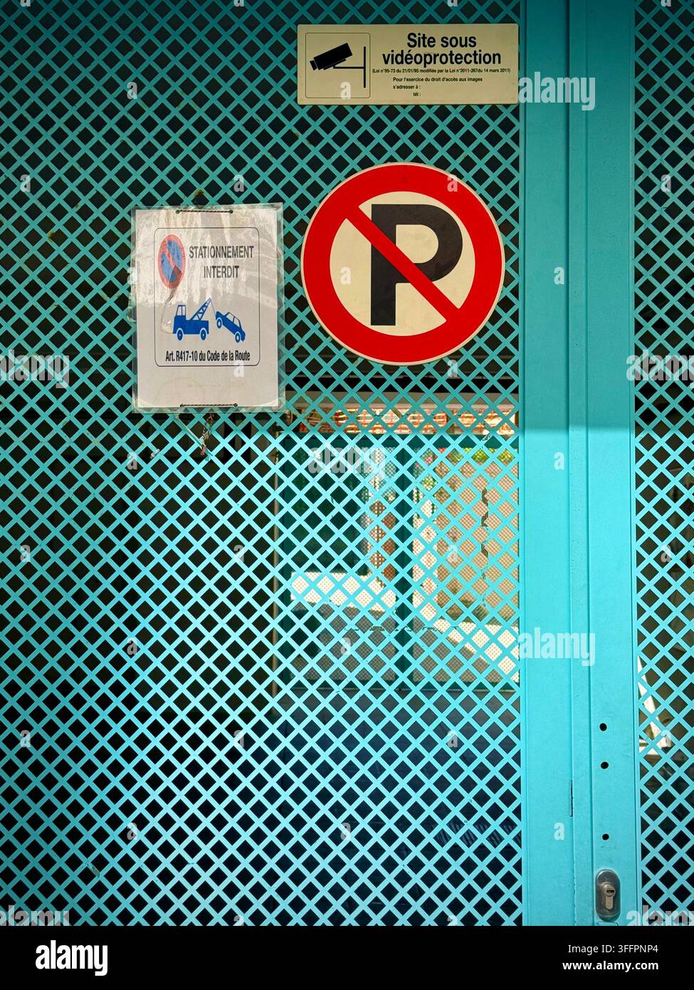 Französischsprachige Parkverbot- und Videoüberwachungsschilder, die an einem türkisfarbenen Metall-Sicherheitstor in Brüssel, Belgien, angebracht sind Stockfoto