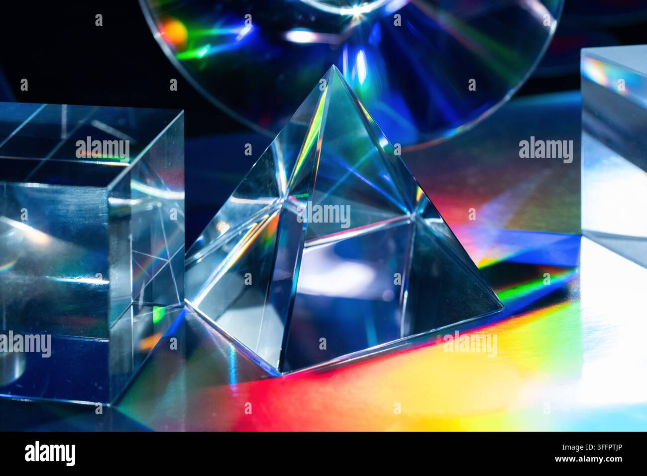 Abstrakte futuristische Komposition aus Glasprismenformen und Kristallblöcken, die lebendiges Regenbogenlicht über eine dunkle Oberfläche reflektieren und einen leuchtenden Tec erzeugen Stockfoto