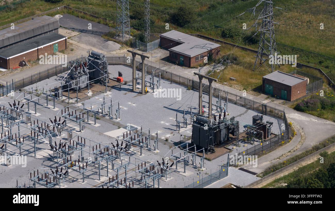 Luftbild einer elektrischen Unterstation mit Transformatoren, Schaltgeräten und Übertragungsstrukturen, die Strom über eine eingezäunte Versorgungsanlage liefern Stockfoto