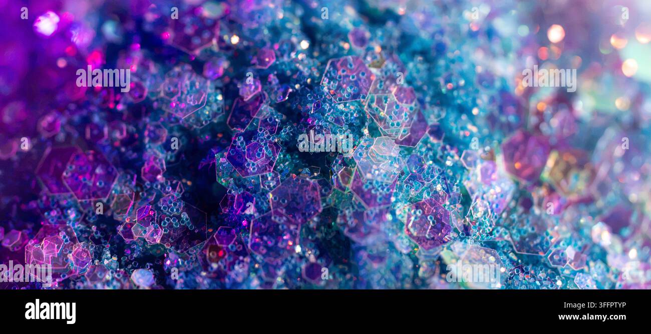 Abstrakte Makroaufnahme von irisierenden hexagonalen Kristallformationen mit leuchtenden blauen, violetten, rosa und türkisfarbenen Tönen, die einen funkelnden farbenfrohen Textur-Effekt erzeugen Stockfoto