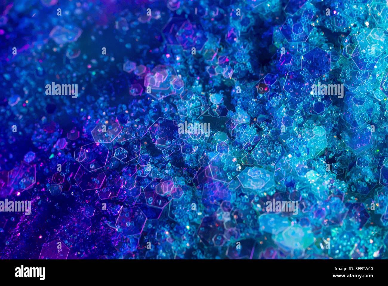 Lebendiger abstrakter Hintergrund mit geschichteten sechseckigen Formen, leuchtenden Partikeln und kristalliner Textur in leuchtenden Blau-, Cyan-, Violett- und Lila-Tönen Stockfoto
