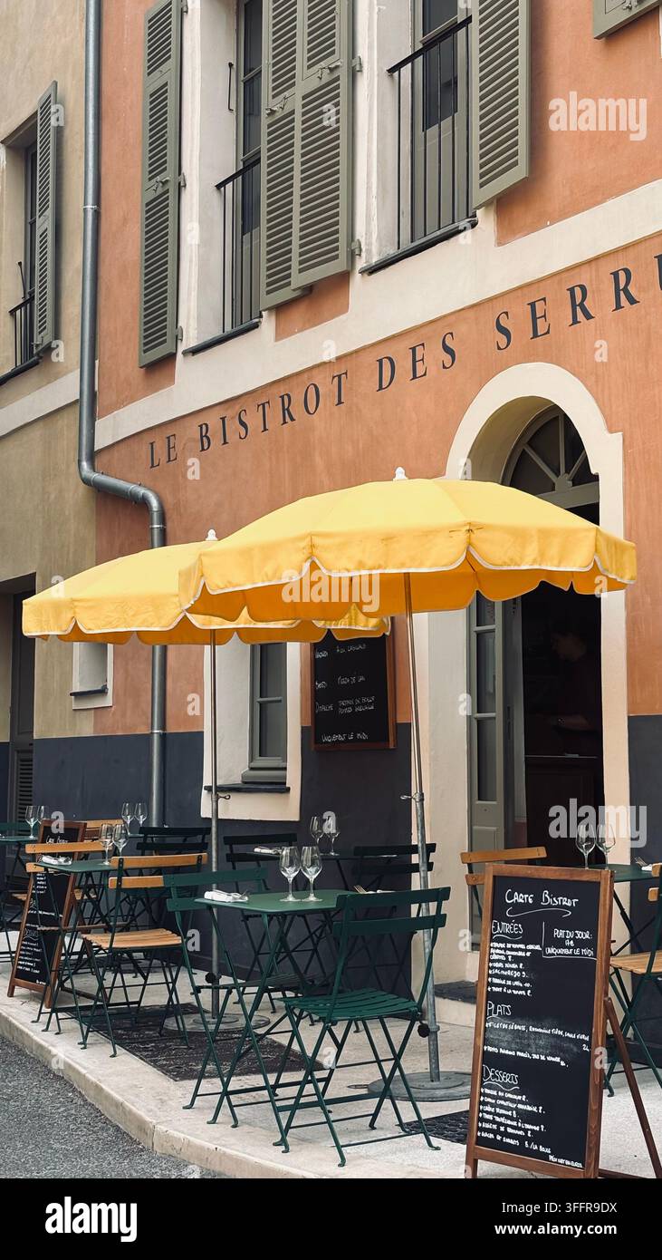 Außenrestaurant-Terrasse mit Tischen, Stühlen und großen Sonnenschirmen in einer europäischen Umgebung Stockfoto