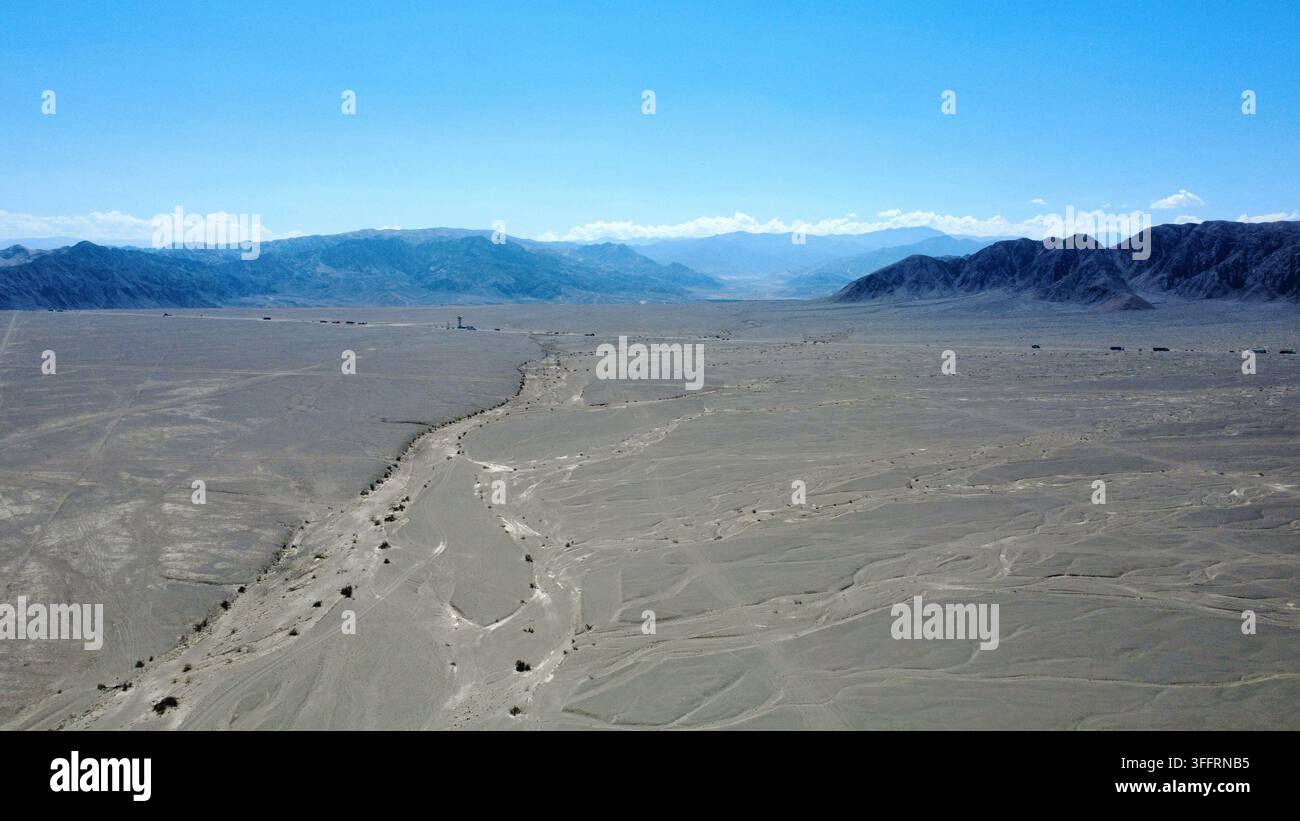 Luftbilddrohnenaufnahme der Nazca-Wüste Pampa mit antiken Geoglyphen und trockenem Flussbett, Nazca, Peru. Im Hintergrund die Anden. Stockfoto