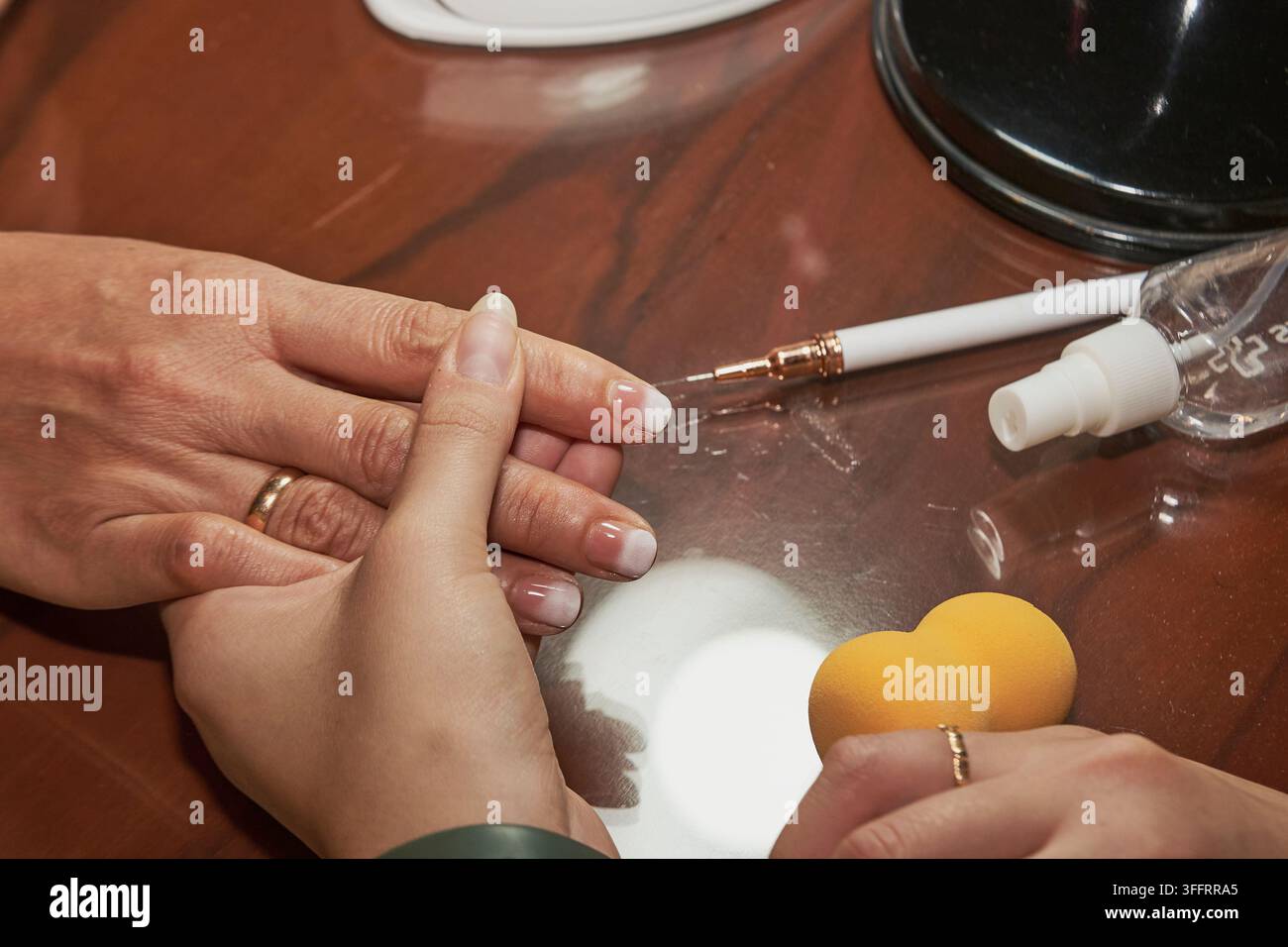 Hände, die eine kosmetische French-Maniküre-Behandlung mit einem Schwamm und Nagelwerkzeugen erhalten Stockfoto