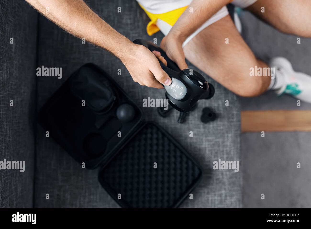 Verwendung einer Massagpistole für Perkussionstherapie und Erholung zur Linderung von Muskelverspannungen. Ideal für die körperliche Rehabilitation und myofasziale Entspannung. Hochqual Stockfoto