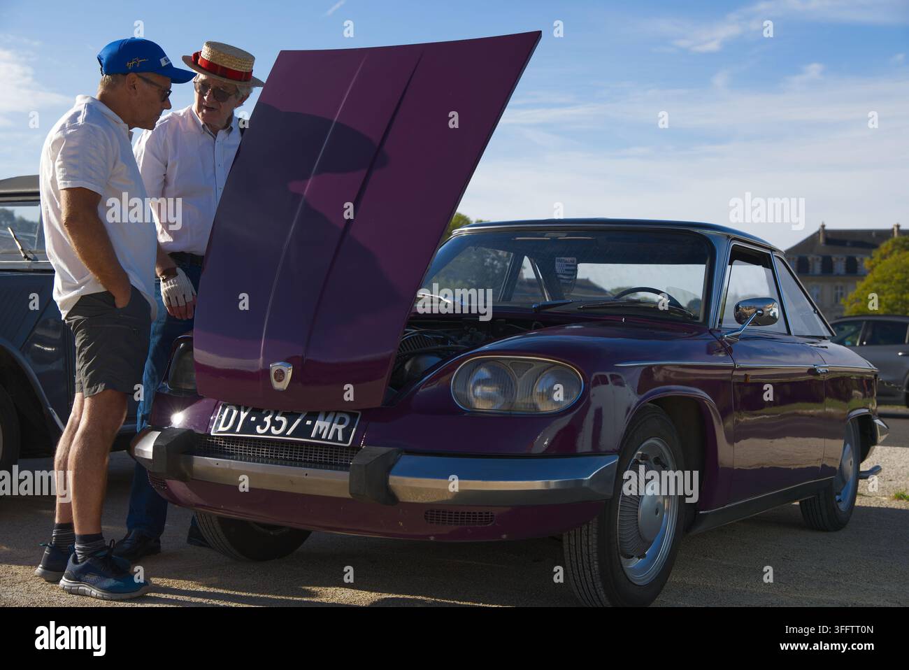 Zwei Männer inspizieren den offenen Motorraum eines klassischen lila Panhard 24 Coupes bei einem Outdoor-Vintage-Autotreffen in Frankreich. Stockfoto