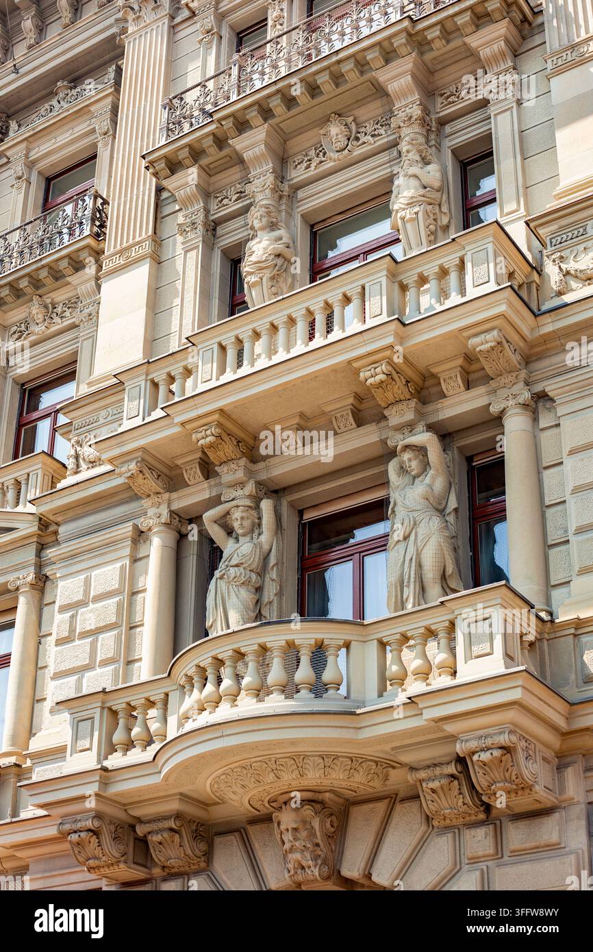 Verzierte neoklassizistische Gebäudefassade mit Karyatidenstatuen, elegantem Balkon und aufwendigen Steinmetzarbeiten Stockfoto
