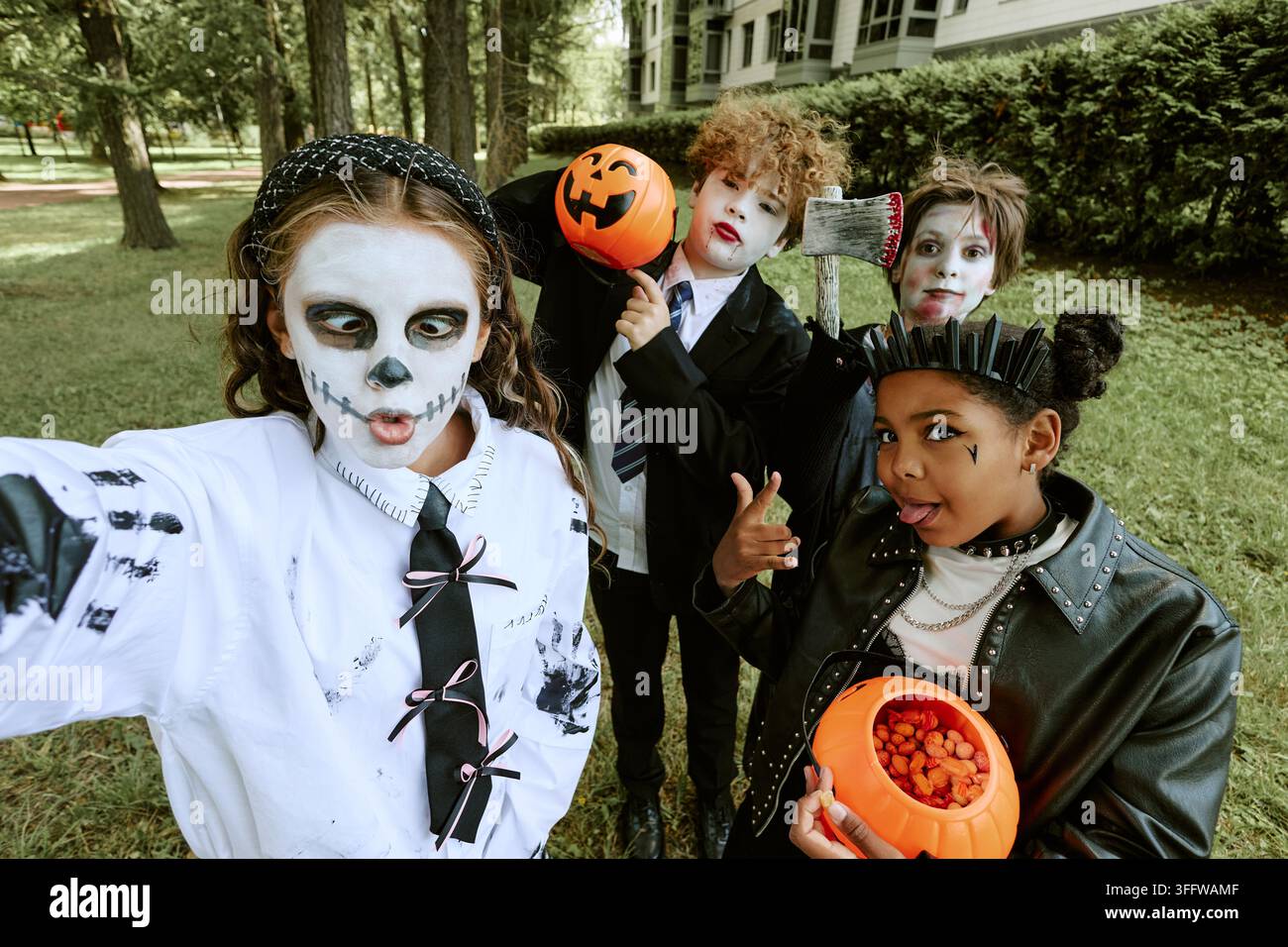 Porträt von vielfältigen Kindern in Halloween-Kostümen, die im Freien ein Selfie machen Stockfoto