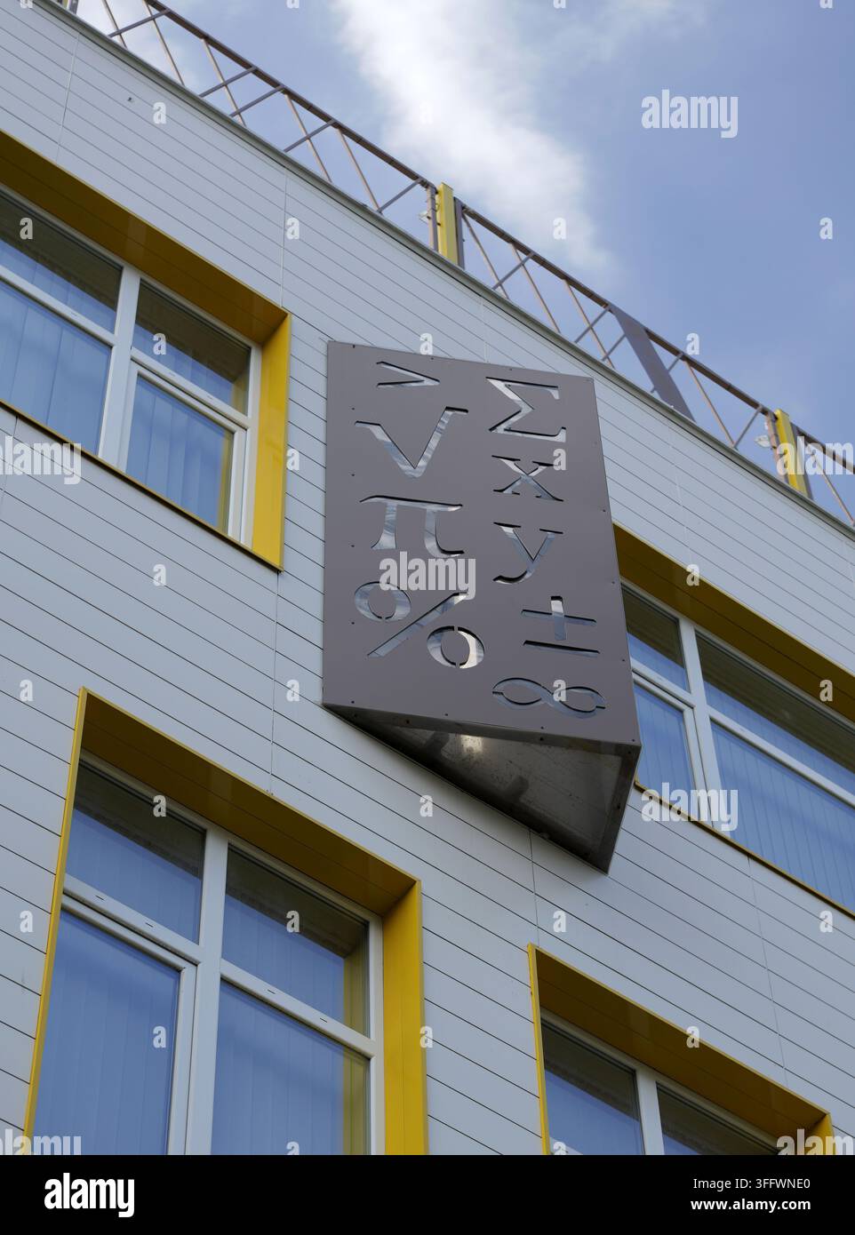 Moderne Schulgebäudefassade mit einem dekorativen Panel aus ausgeschnittenen mathematischen Symbolen, das Lernen, Wissenschaft und Bildung repräsentiert. Bulgarien, Stockfoto