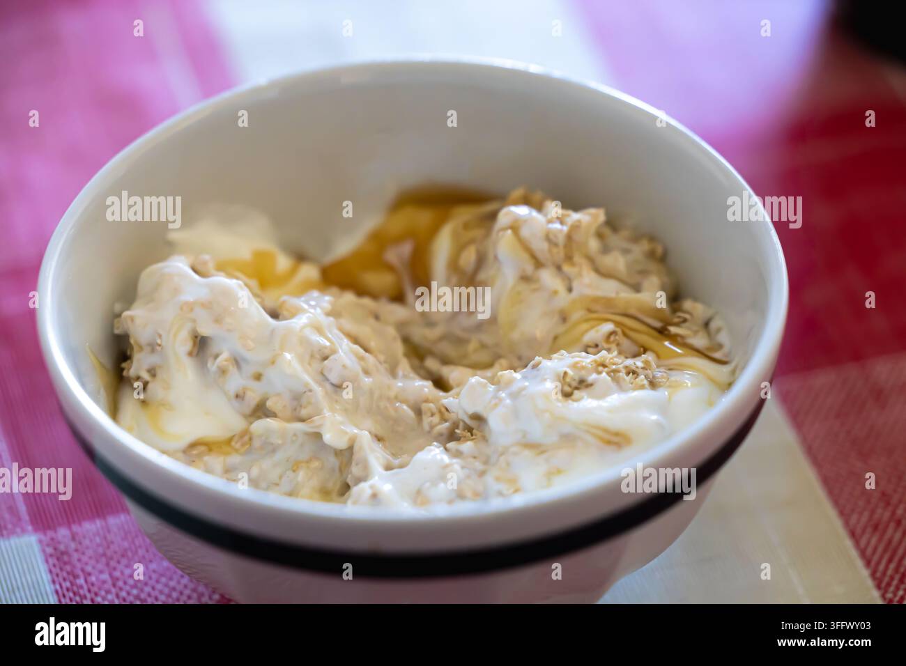 Eine überkopf gehaltene Nahaufnahme zeigt eine kleine, cremefarbene Keramikschale, die mit einer gesunden Frühstücksschüssel gefüllt ist Stockfoto