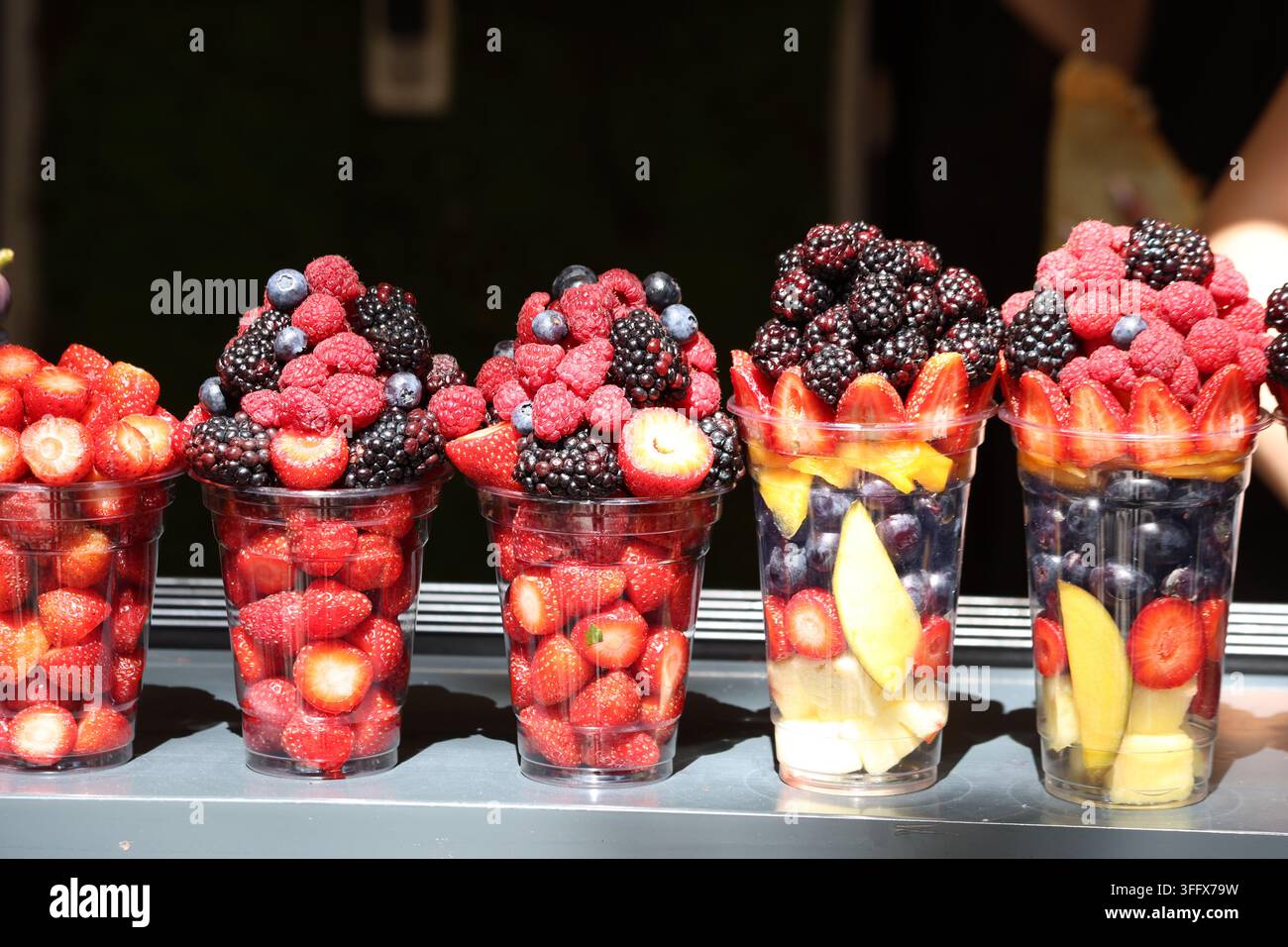 Frische Beeren- und gemischte Obstsalatbecher, die in einem Marktstand zum Verkauf angeboten werden Stockfoto