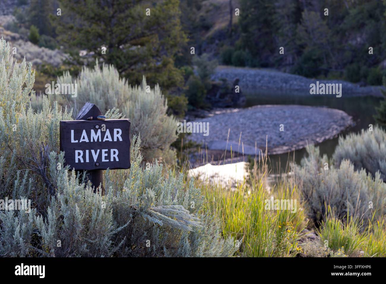 Rustikaless Holzschild mit der Aufschrift Lamar River, eingerahmt von Salbeibüschen und Wald im Yellowstone-Nationalpark, Wyoming. Stockfoto
