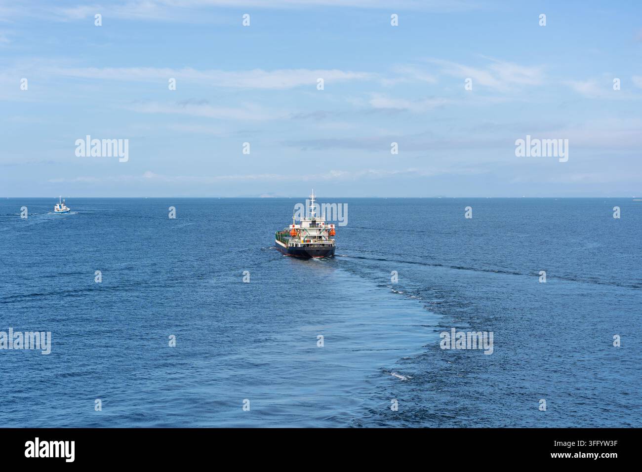Kleines Frachtschiff segelt ruhiges blaues Wasser in die offene See an einem sonnigen Tag Stockfoto