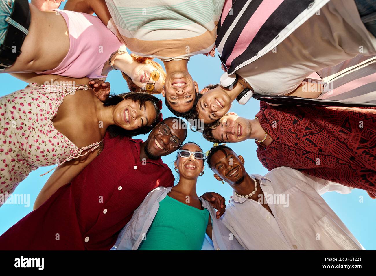 Gruppe von verschiedenen glücklichen Freunden, die in einer Runde stehen, lächeln und ein Gefühl von Einheit und Gemeinschaft schaffen Stockfoto
