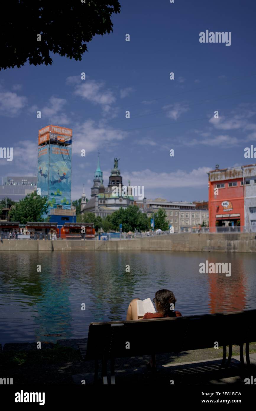 Eine Person liest ein Buch am Wasser im Alten Hafen von Montreal, Quebec, Kanada, an einem Sommertag. Stockfoto