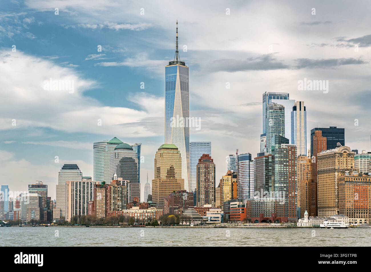 New York, NY, USA – 13. April 2026: Blick auf die Skyline von Lower Manhattan aus gesehen vom New York Harbor mit dramatischen Wolken und einem Blick auf die Freedo Stockfoto