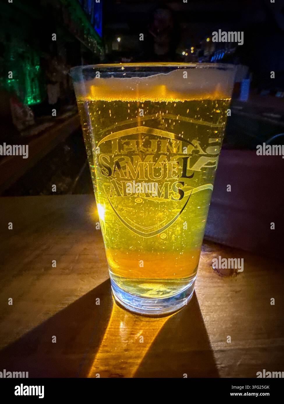 Pint goldenes Bier-Lager-Ale von Samuel Adams an einer Bar in New York, von den Barlichtern hinterleuchtet. Keine Menschen Stockfoto