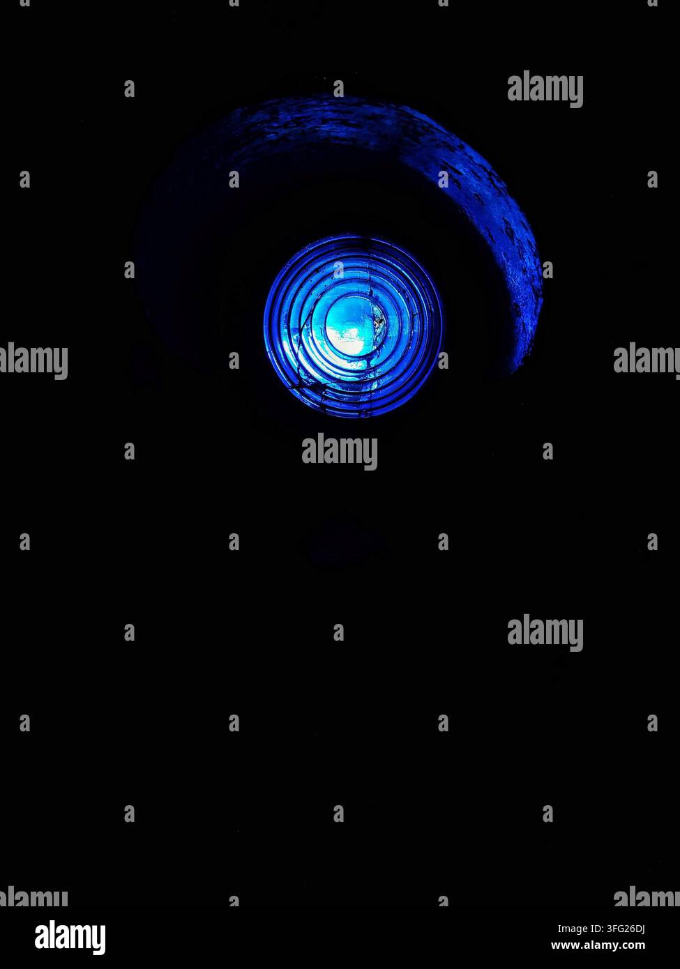 Rundes blaues Licht leuchtet hell vor dunklem schwarzem Hintergrund. Minimalistische Komposition vermittelt ein Gefühl von futuristischer Technologie und Mystik. Stockfoto