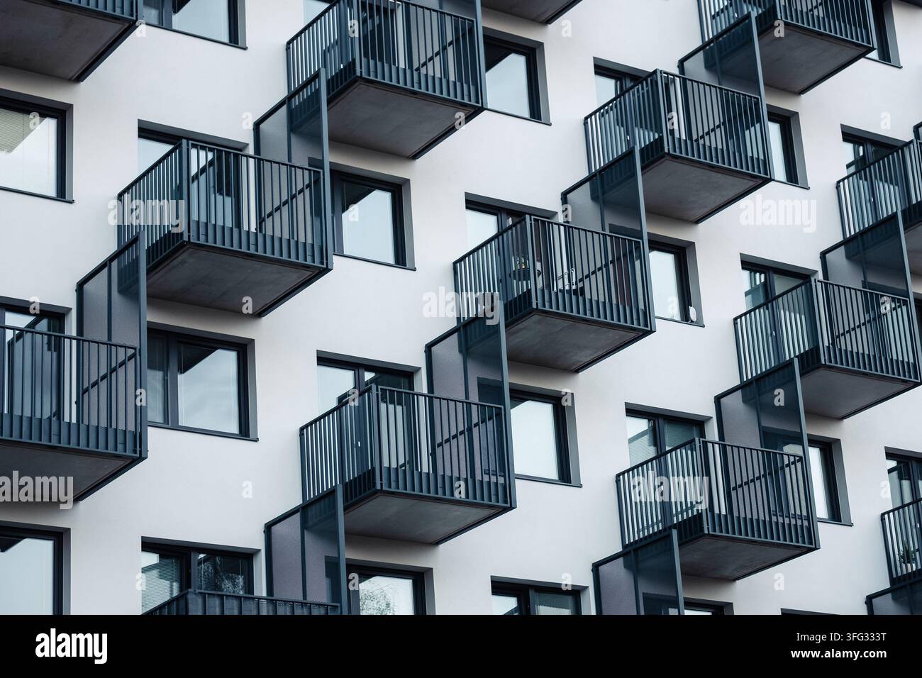 Fassade eines modernen Architekturgebäudes mit geometrisch versetzten schwarzen Balkonen, Fenstern, minimalistischer Außenarchitektur, urbanem Wohnhaus, Immobilien-Design, patt Stockfoto