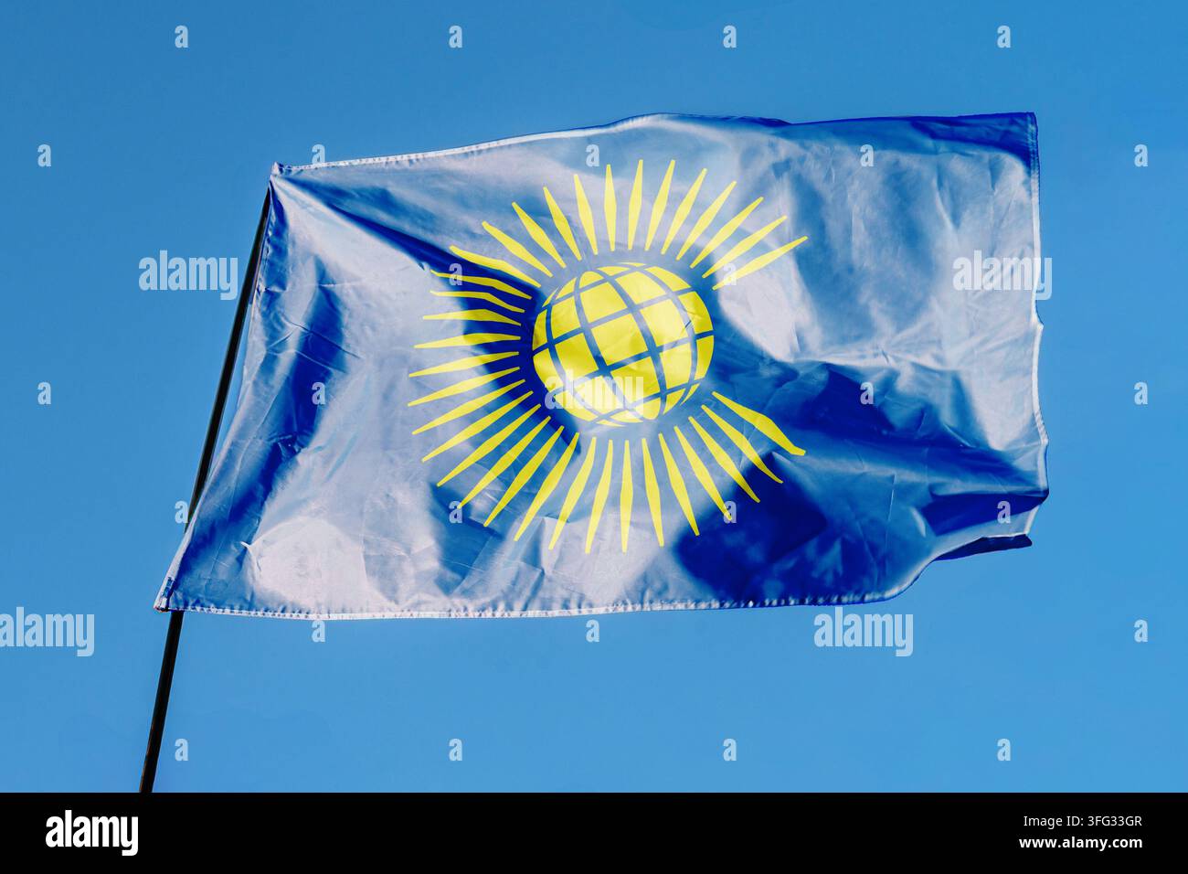 Flagge des Commonwealth der Nationen. Fahne weht im Wind vor einem klaren blauen Himmel, flatternd an einer Fahnenstange im Freien. Heller Sonnentag, Stofftextur Stockfoto