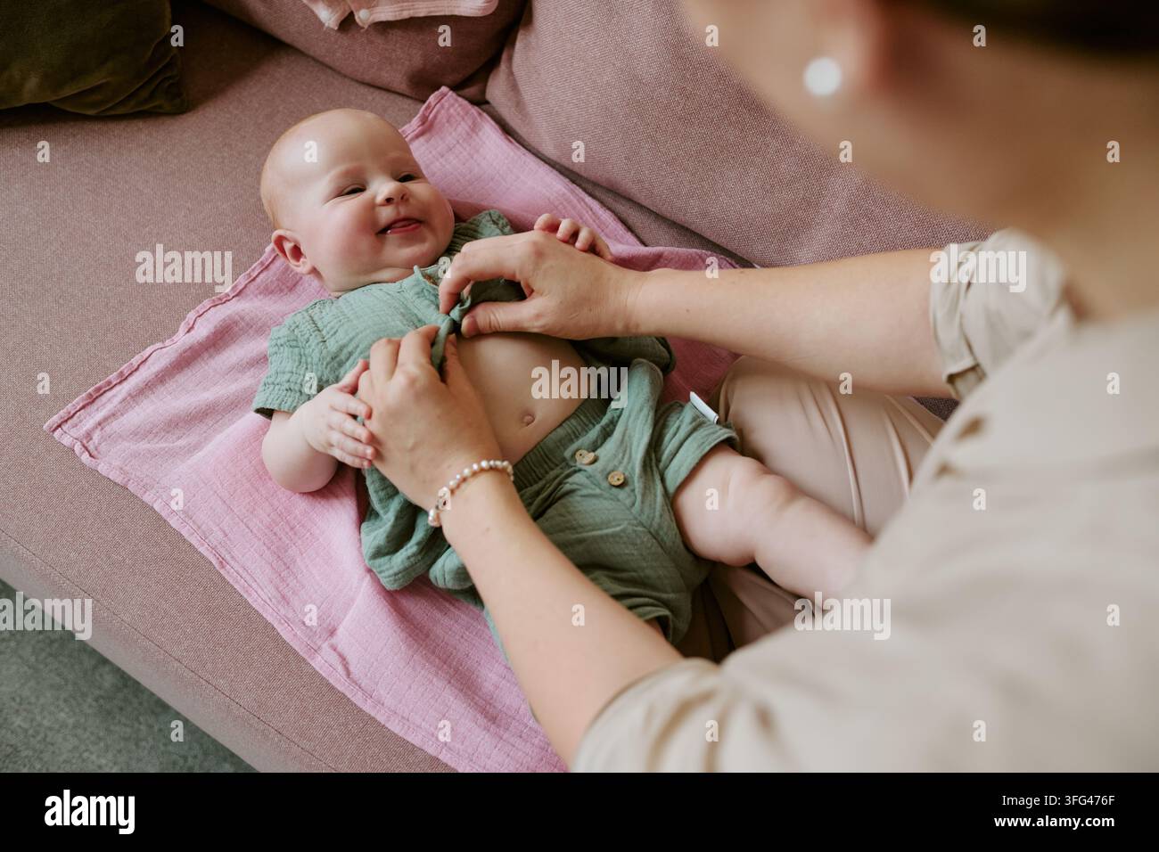 Mutter zieht glücklich Babyjungen zu Hause für die Kinderbetreuung an Stockfoto