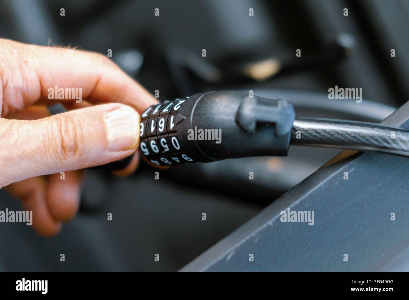 eine Hand, die den Sicherheitscode für ein Kabelschloss einstellt, Nahaufnahme im Freien Stockfoto
