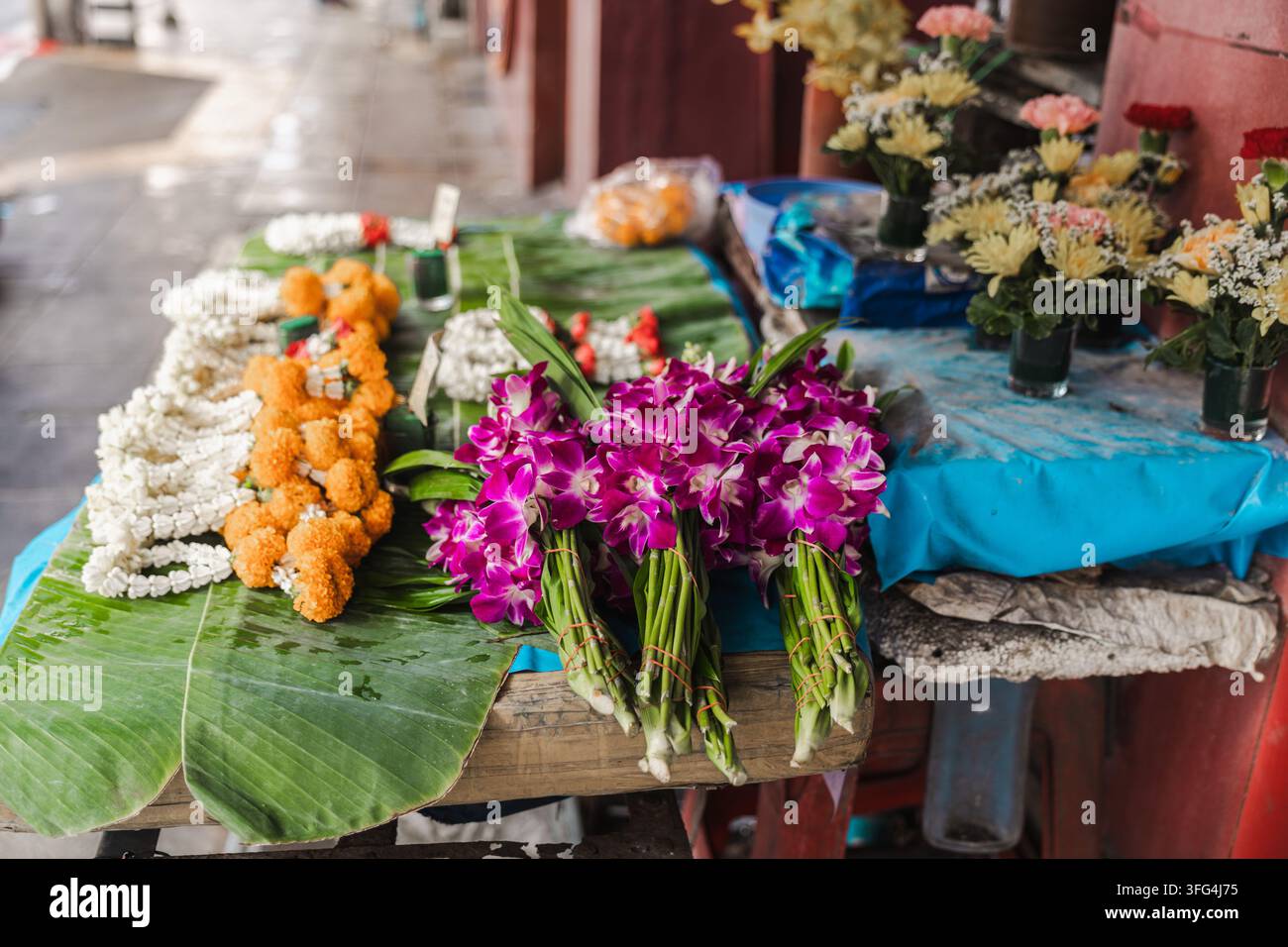 Bunte Orchideensträuße und Girlanden an einem Blumenstand auf der Straße in Bangkok Stockfoto