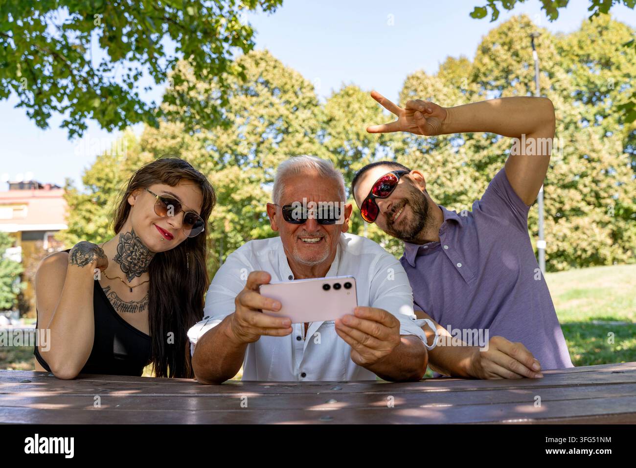 Glückliche Familienbindung im Freien, lächelnd und Erinnerungen mit dem Smartphone festhalten Stockfoto