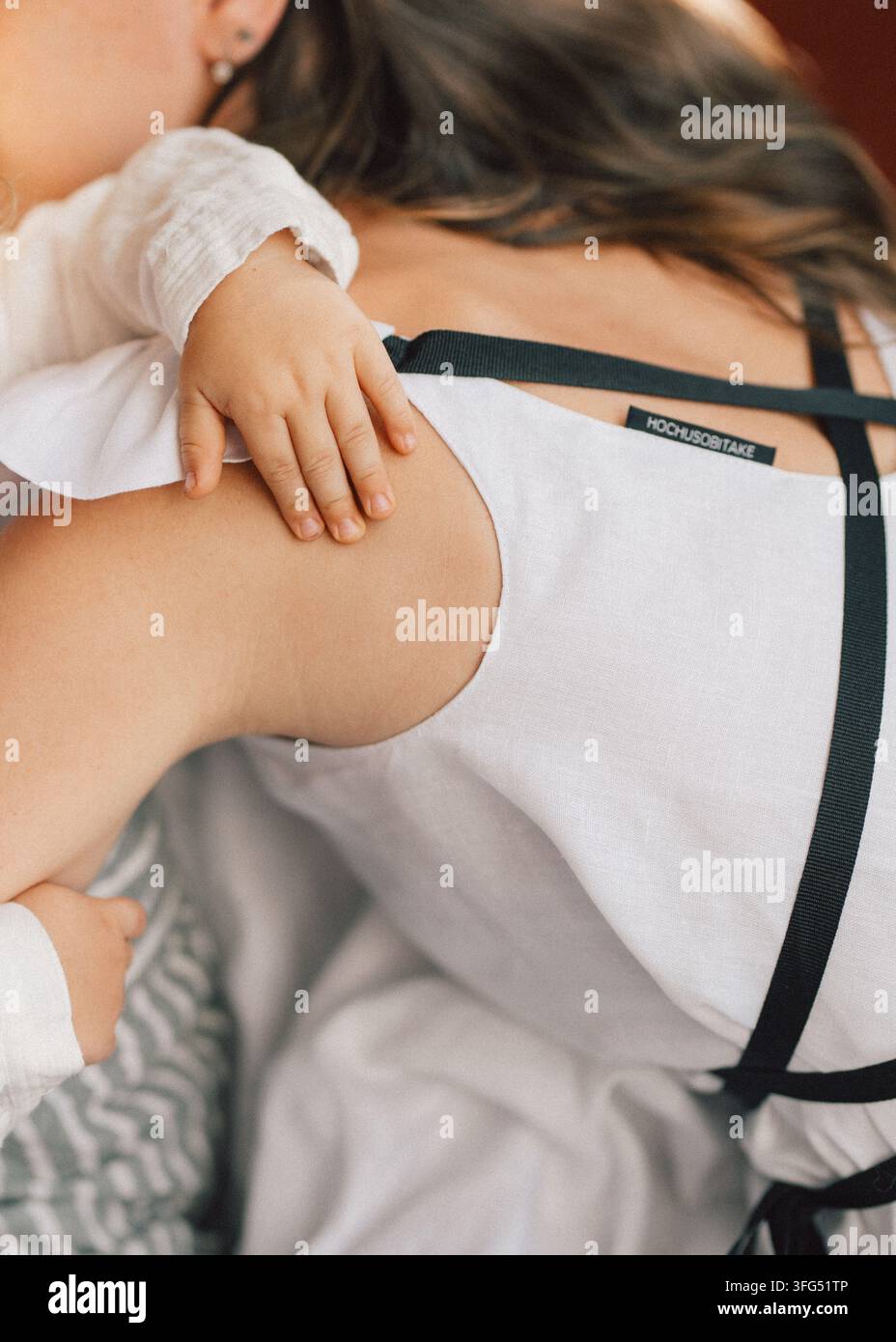 Nahaufnahme einer Mutter, die ihr Kleinkind umarmt, warme Hauttöne, intimes Familienporträt Stockfoto