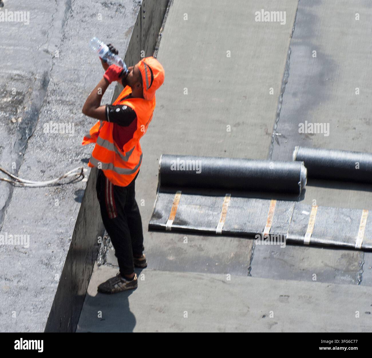 Ein Bauarbeiter trinkt bei heißem Wetter Wasser. Stockfoto