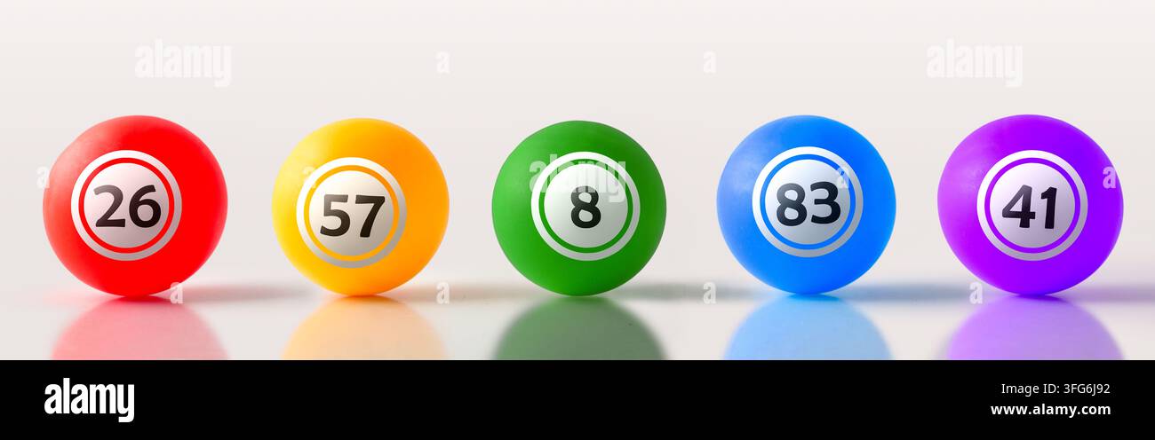 Fünf glänzende rote, orange, grüne, blaue und violette nummerierte Lotteriekugeln sind auf einer sauberen Oberfläche ausgerichtet und schaffen ein helles, verspieltes Glücksspielkonzept. Stockfoto