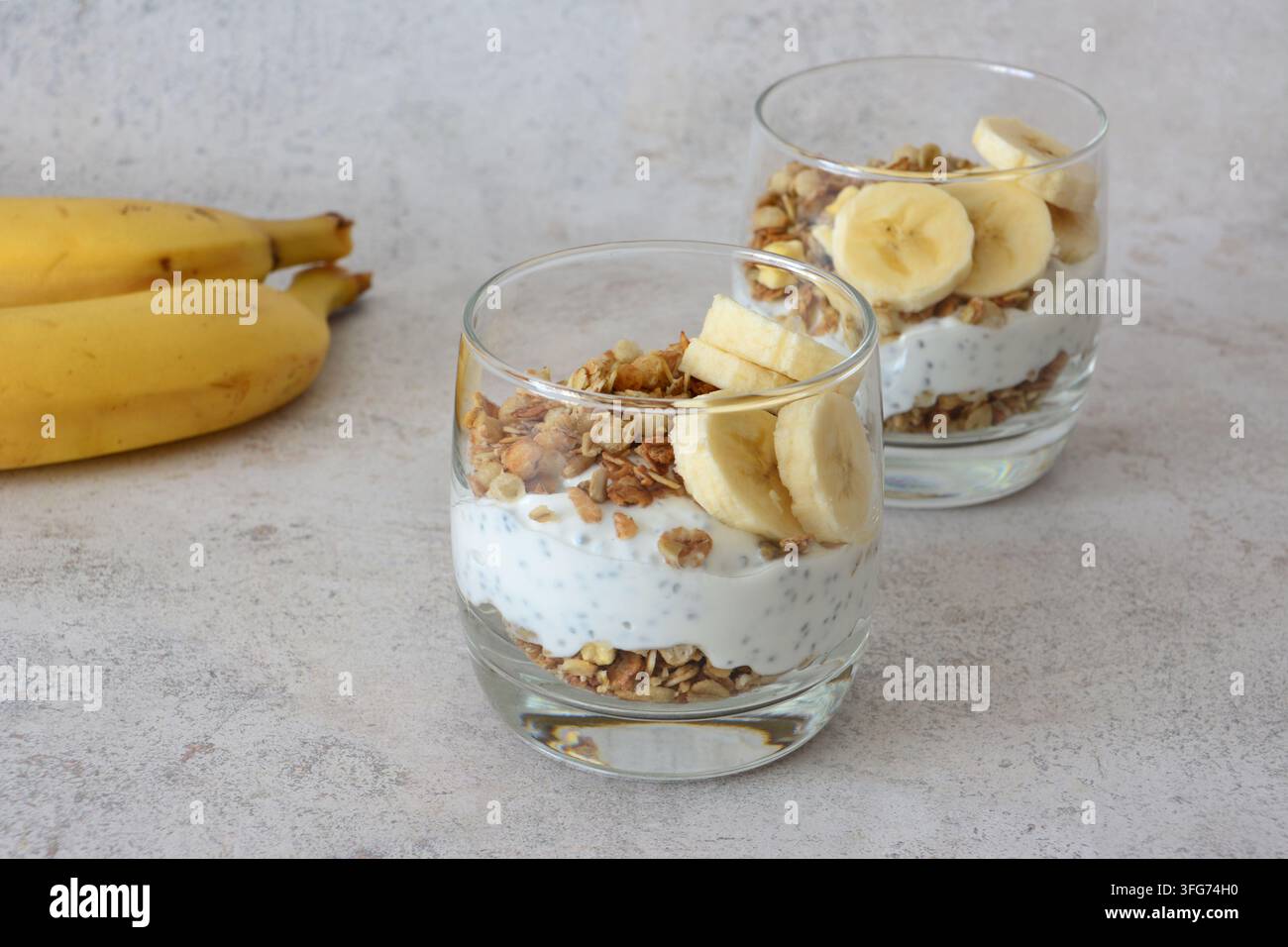 Banana Parfaits mit Granola und Chiasamen und einige Bananen im Nahaufnahme Stockfoto