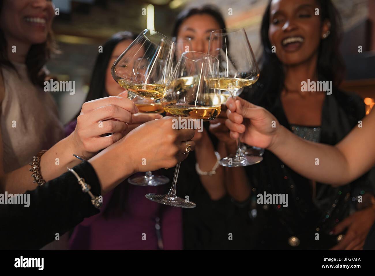 Freunde versammeln sich in einem Restaurant, um gemeinsam zu feiern, während sie Champagnergläser zu einem freudigen Prost erheben. Stockfoto