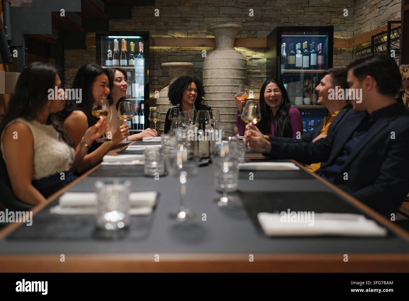 Eine Gruppe von Freunden genießt ein Abendessen und Getränke in einem Restaurant und führt lebhafte Gespräche. Die Atmosphäre ist warm und einladend. Stockfoto