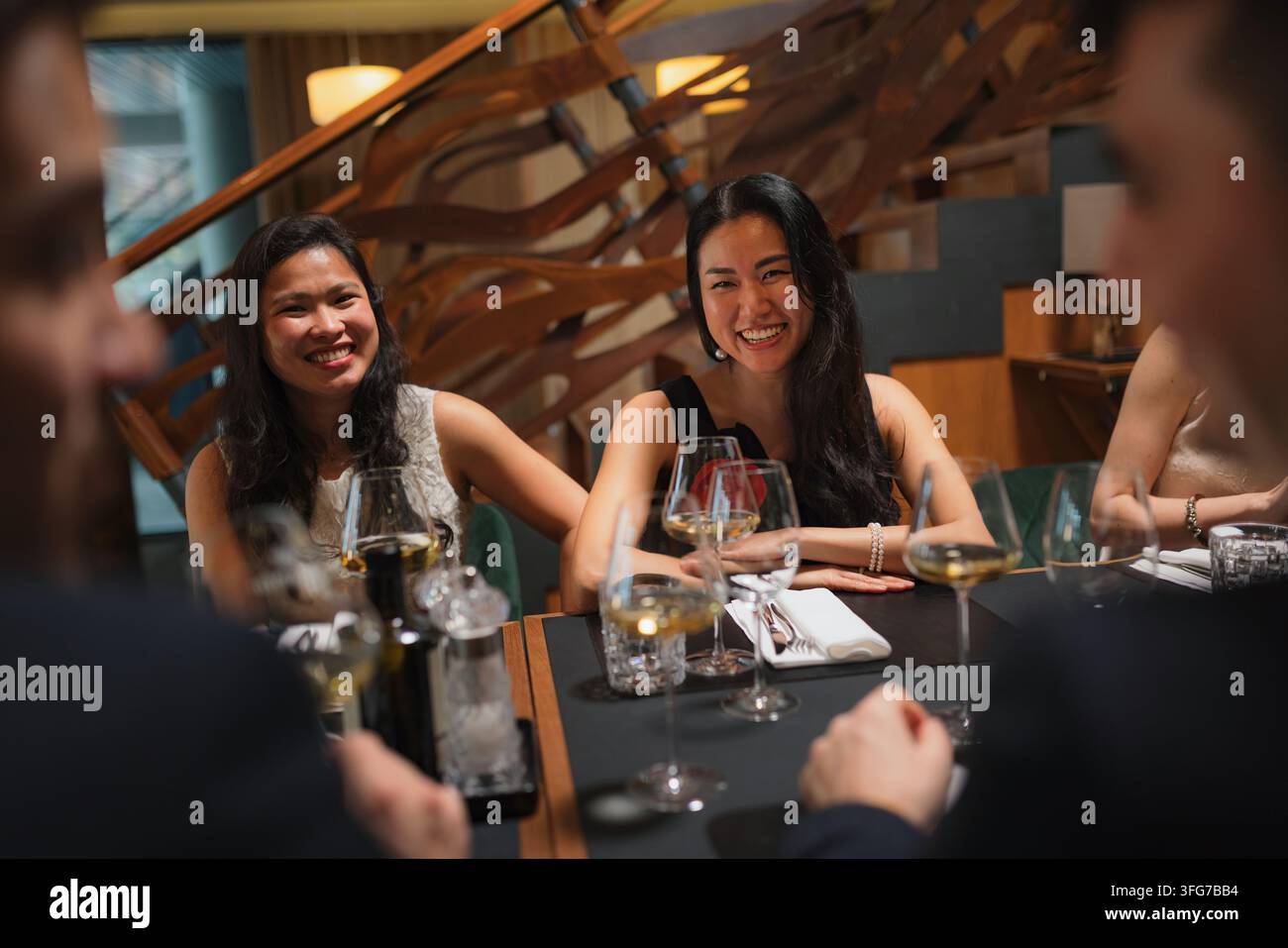 Eine vielfältige Gruppe von Freunden teilt Essen und Getränke während eines lebhaften Abendgesprächs bei einem Restaurantfest. Stockfoto