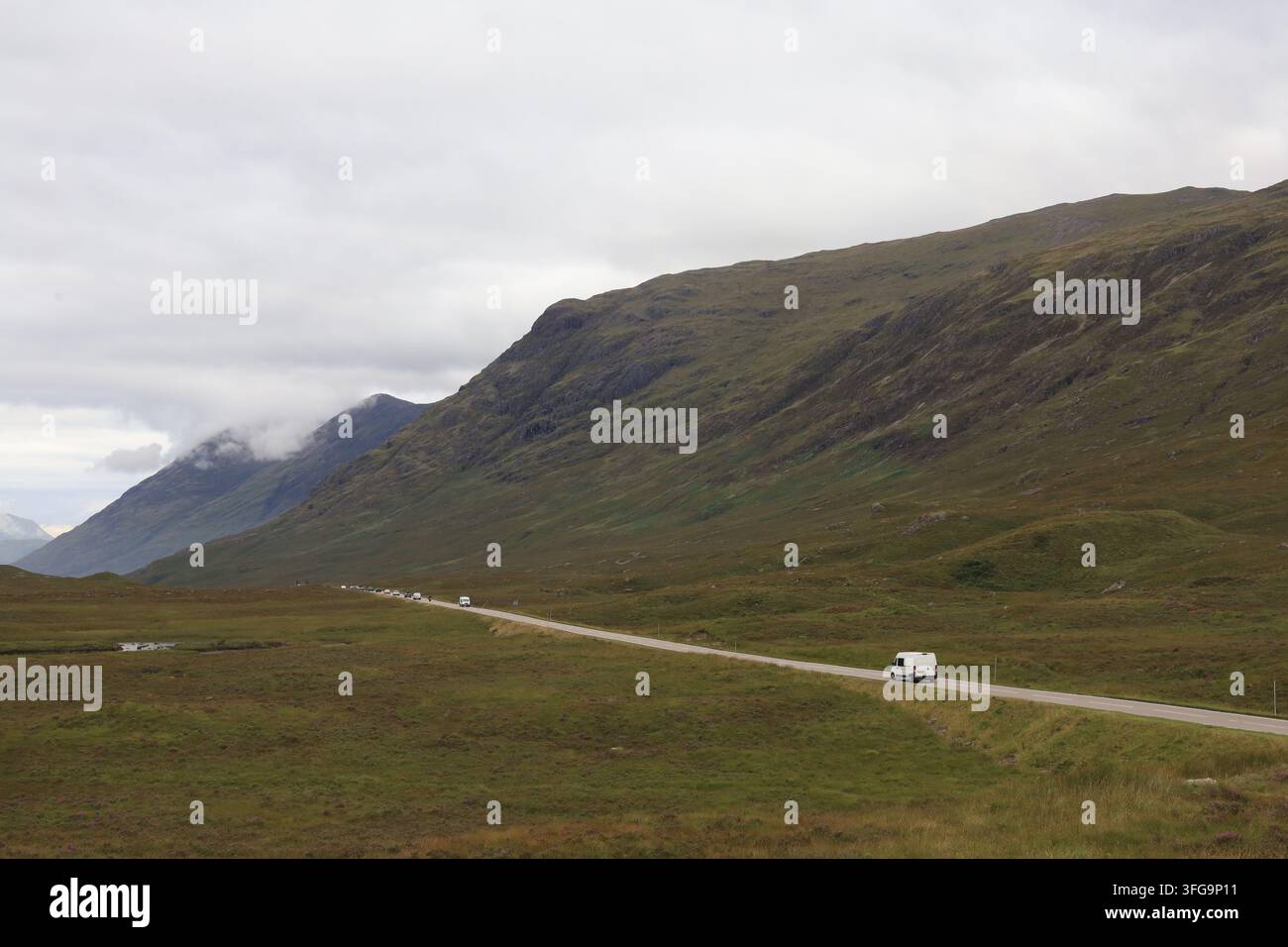 Ein malerischer Blick auf die wunderschönen Landschaften Schottlands, die einen Wohnwagen und eine Spur von Autos unter wolkenverhangenem Himmel in den Schatten stellen, August 2026. Stockfoto
