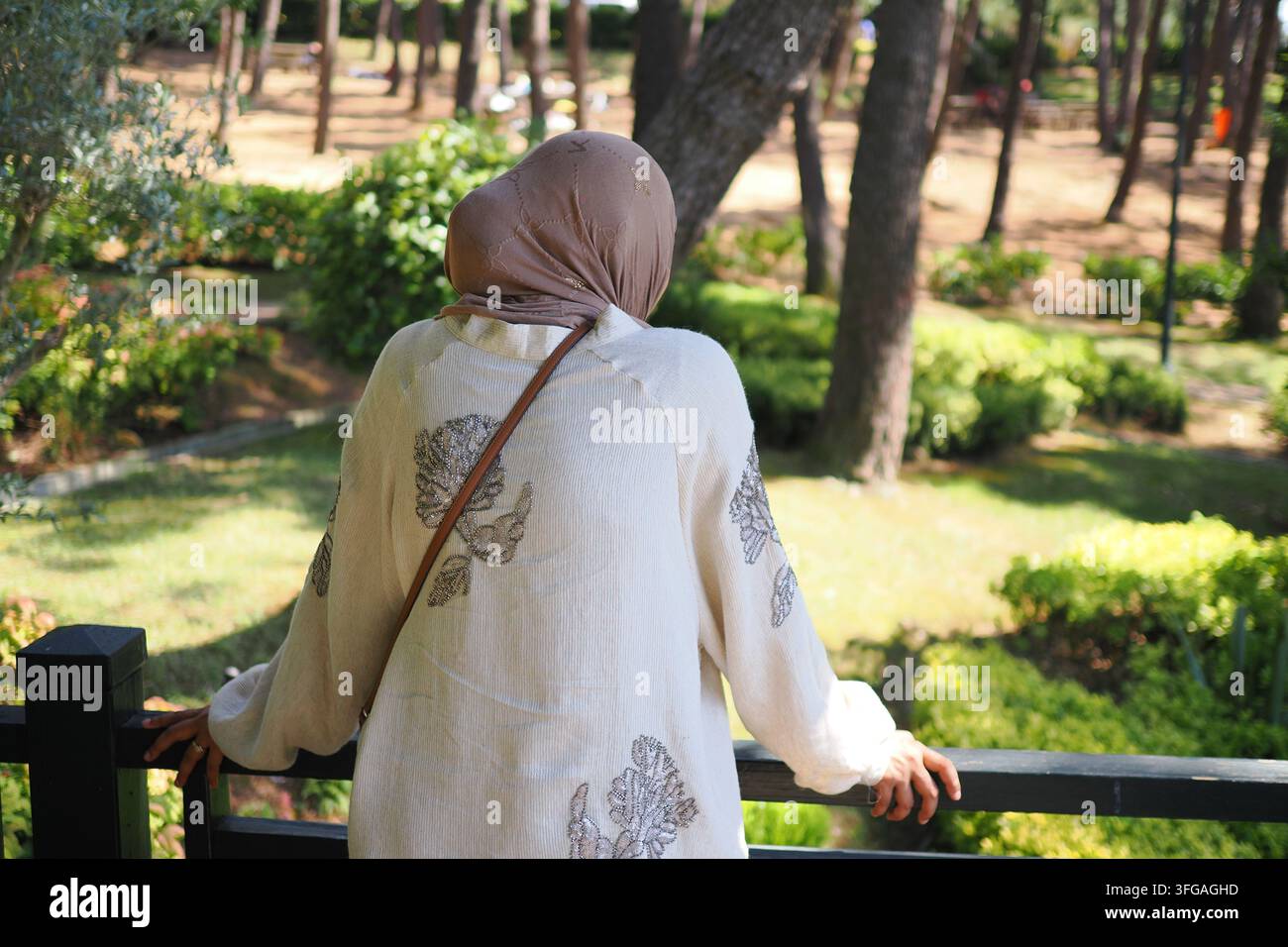 Frau betrachtet einen Garten mit Bäumen in einem Park am Tag Stockfoto