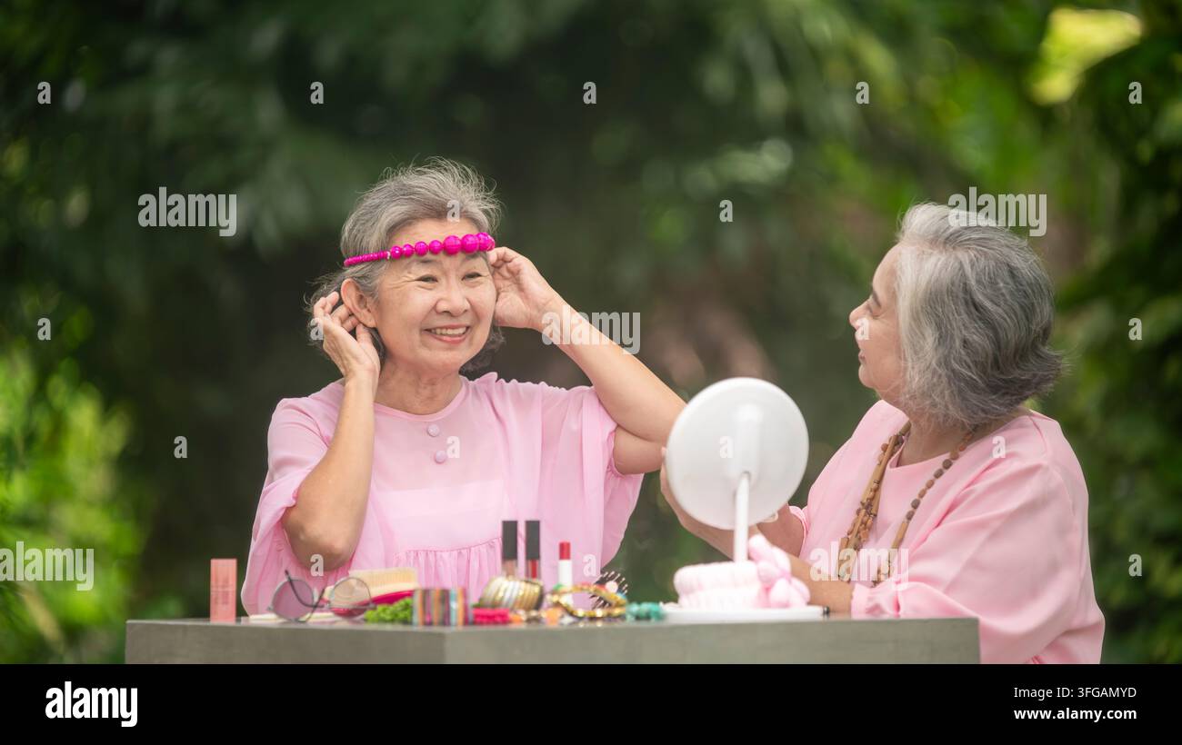 Ältere Frauen genießen die Natur und konzentrieren sich auf schöne Dekorationen und Ornamente im Grün um sie herum, was den Lebensstil der Seniorenferien ausmacht. Stockfoto