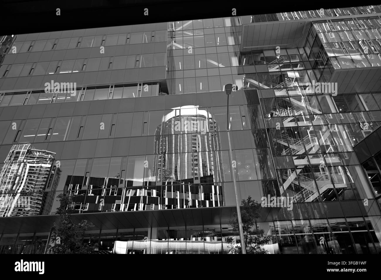 Modernes Glasbürogebäude mit reflektierenden Fenstern in der Innenstadt von Seattle, das urbane Architektur, geschichtete Reflexionen und zeitgenössisches Stadtbild einfängt Stockfoto