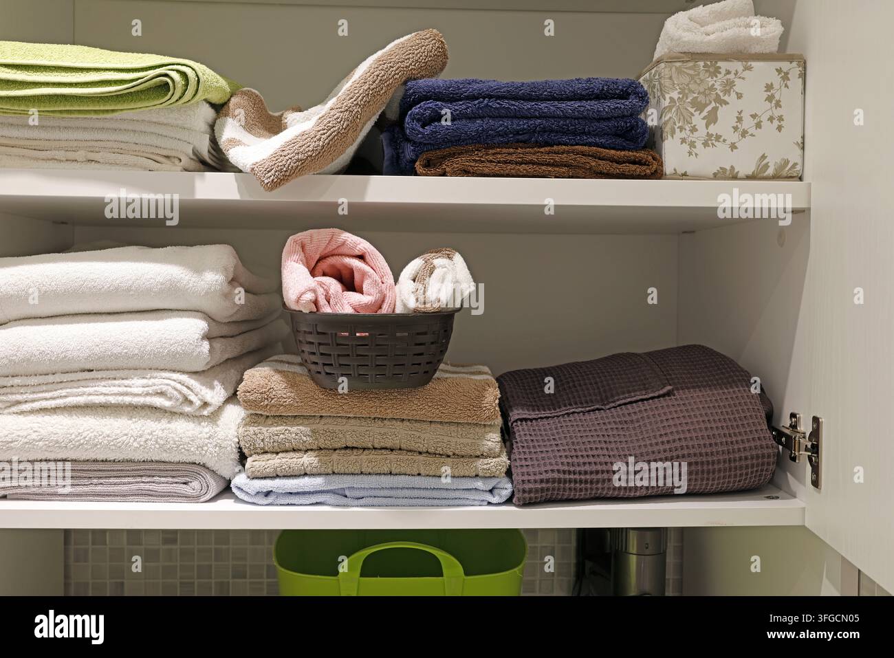 Ordentlich gefaltete Handtücher, die auf weißen Regalen im Wäscheschrank angeordnet sind. Stockfoto