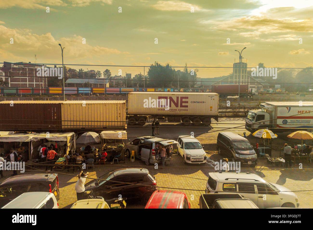 12. September 2026 - Panoramablick auf One Ocean Network Container-LKW mitten im Abendverkehr und Straßenmarkt zur Goldenen Stunde in Mlolongo, Kenia Stockfoto