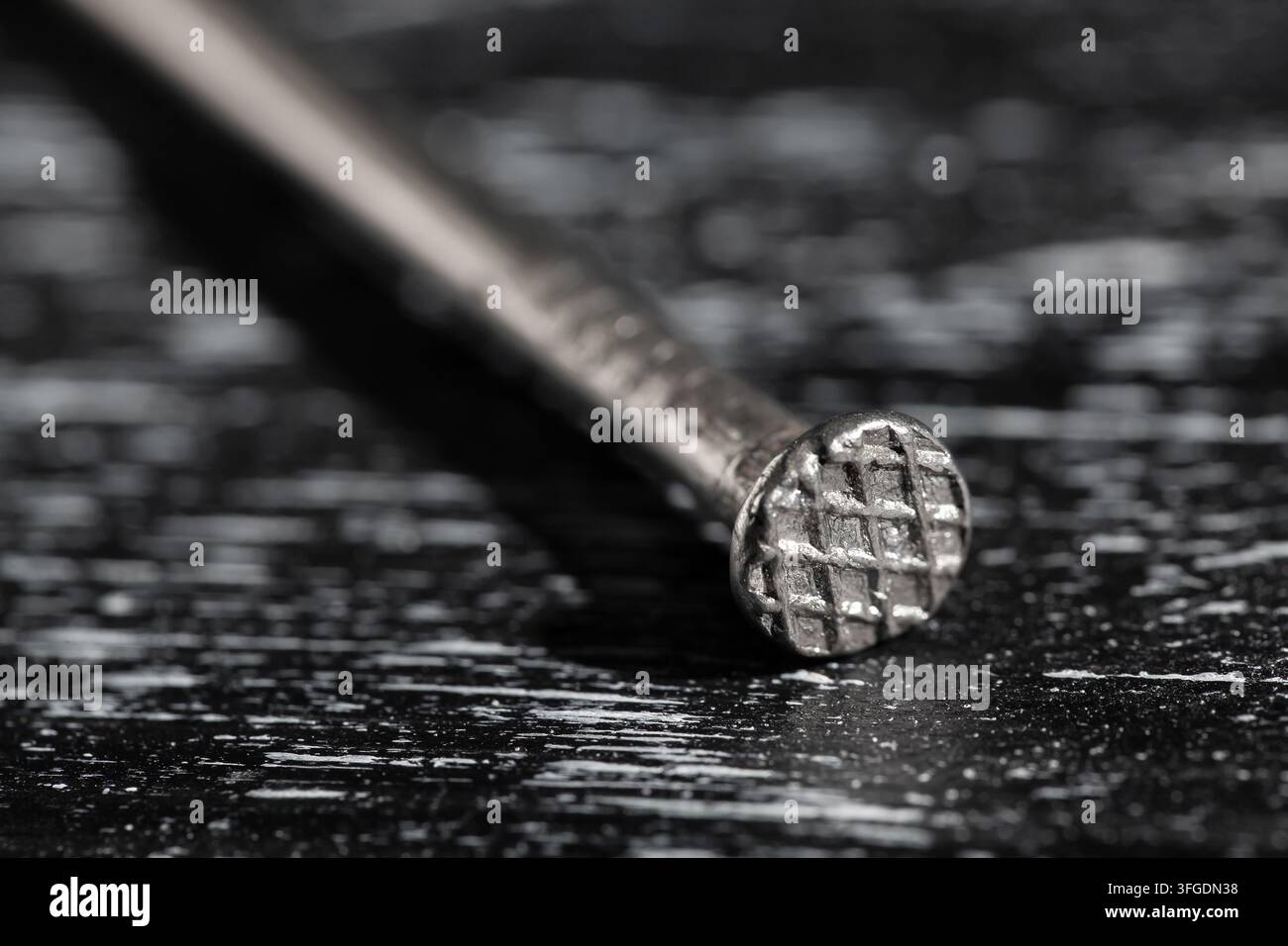 eine Nagelkopf auf schwarzem Holzuntergrund Makro Stockfoto