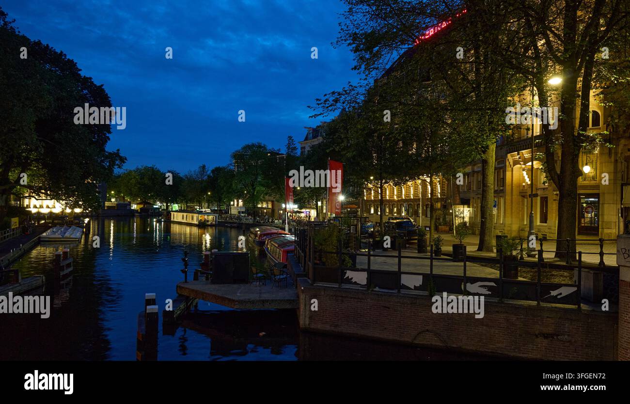 Amsterdamer Kanal in der Dämmerung mit beleuchteten historischen Gebäuden Stockfoto