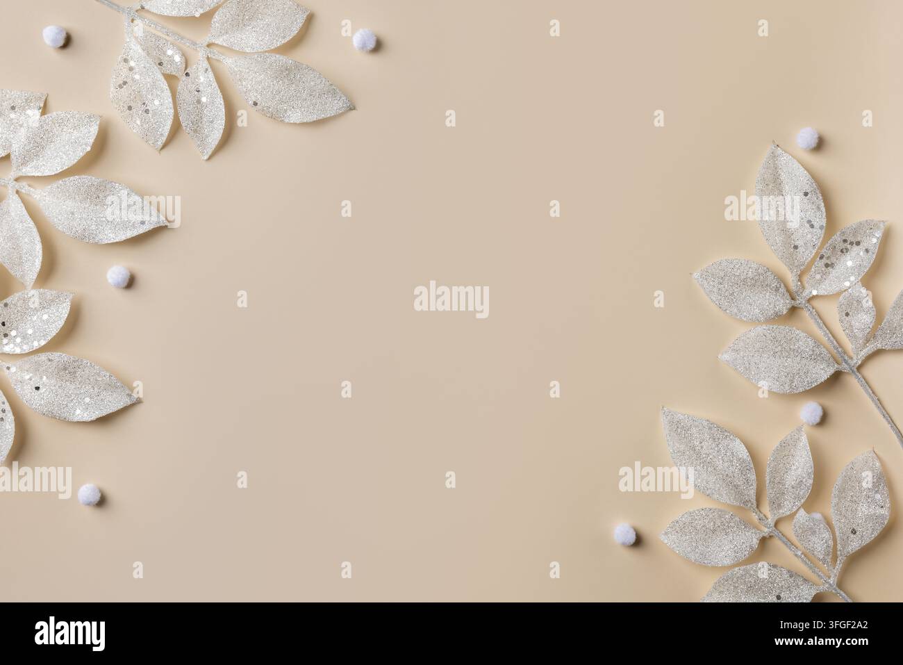 Silberne Glitzerblätter umrahmen einen beigen Weihnachts-Hintergrund mit zentralem Kopierraum für Neujahrskarten, Banner oder festliches Design Stockfoto