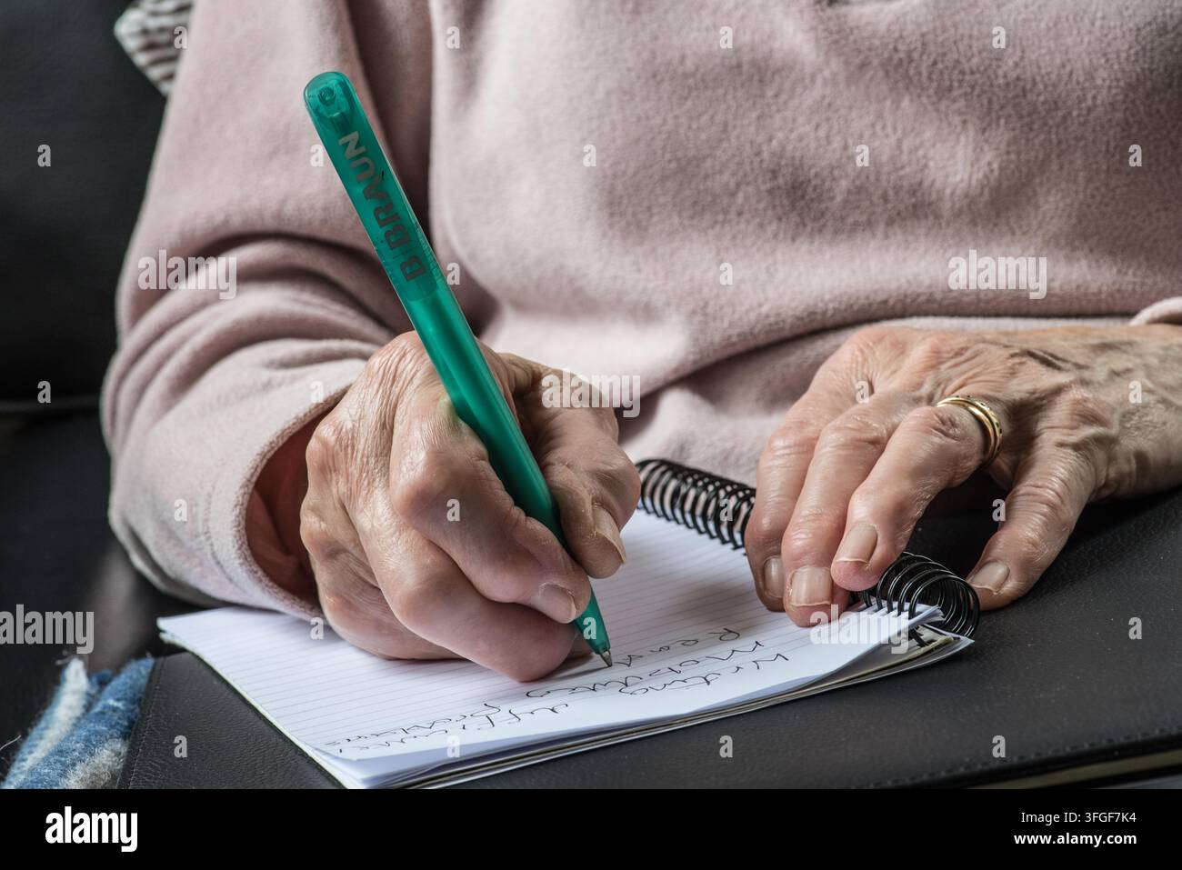 Nahaufnahme der Hände älterer Personen, die Falten und sichtbare Gelenkveränderungen zeigen, wobei eine Gelenkvergrößerung das Schreiben beeinträchtigen kann. Stockfoto