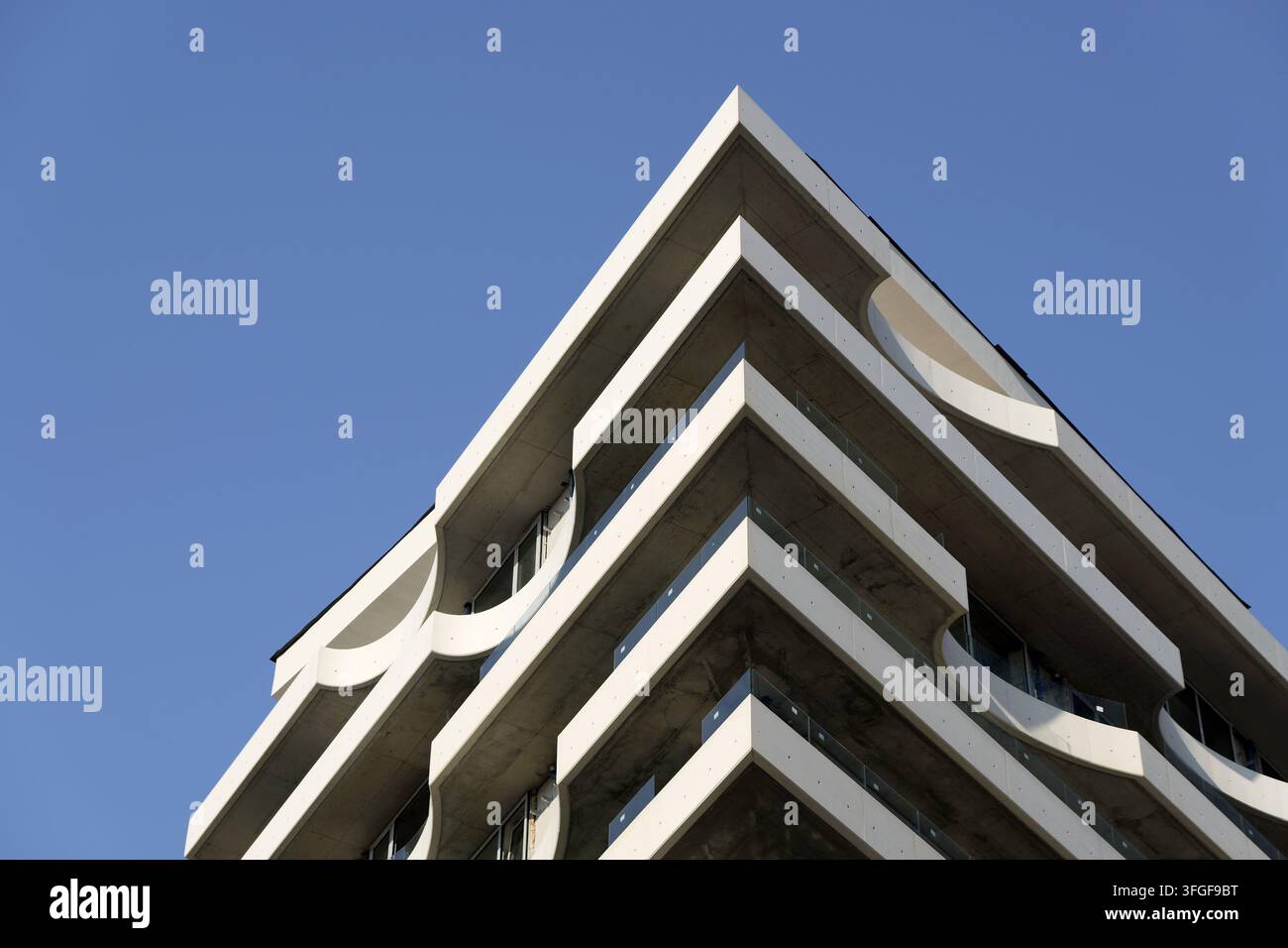 Moderne Wohnhausfassade mit Balkonen mit halbrunden Designelementen und klaren Linien vor einem klaren blauen Himmel. Bulgarien, Varna, 11 s Stockfoto