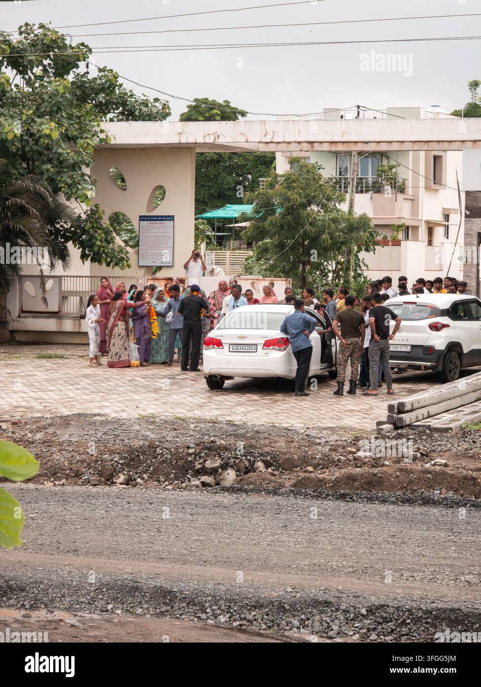 Eine vielfältige Gruppe von Menschen versammelt sich in einem Wohngebiet in Gujarat, Indien, und unterhält sich bei Gemeinschaftsaktivitäten. Die Szene fängt das Es - Smartphone-aufgenommenes Stockfoto
