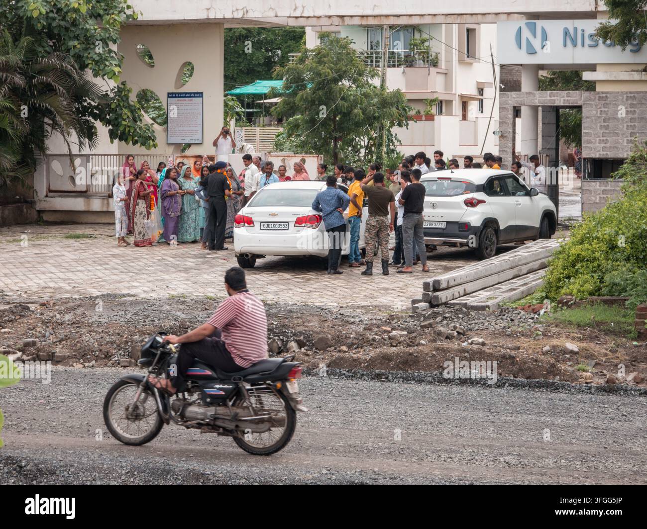 Eine vielfältige Gruppe von Menschen versammelt sich in einem Wohngebiet in Gujarat, Indien, und unterhält sich bei Gemeinschaftsaktivitäten. Die Szene fängt das Es - Smartphone-aufgenommenes Stockfoto